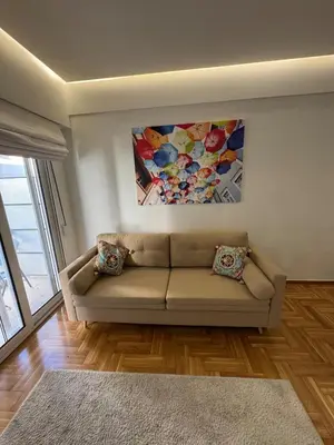 a living room with a couch and a painting on the wall at AtticNest in Athens