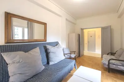 a living room with a blue couch and a mirror at Spacious and bright apt in Eksarchia in Athens
