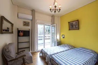 a bedroom with a bed and a chair and a window at Spacious and bright apt in Eksarchia in Athens