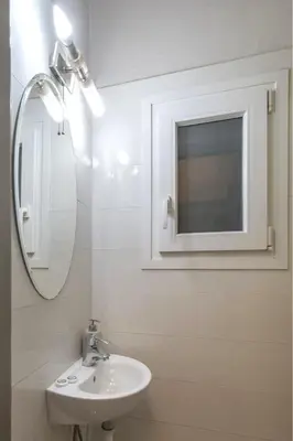 a white bathroom with a sink and a mirror at Spacious and bright apt in Eksarchia in Athens