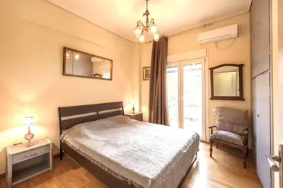 a bedroom with a bed and a chair and a mirror at Spacious and bright apt in Eksarchia in Athens