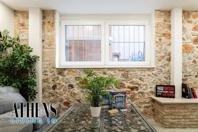 a living room with a glass table in front of a stone wall at Classic Residence A1 apt - 3ppl in Athens