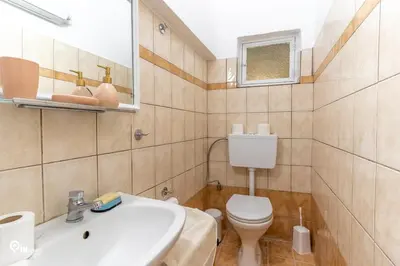 a bathroom with a white sink and a toilet at Gardenia - Cozy House Near Piraeus in Piraeus