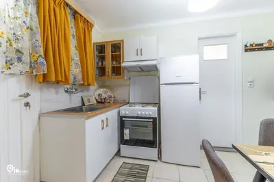 a small kitchen with white cabinets and a refrigerator at Orchid - Stylish Home Near Piraeus in Piraeus