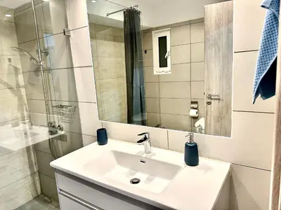 a white bathroom with a sink and a mirror at 3BD next to National Archaeological Museum in Athens