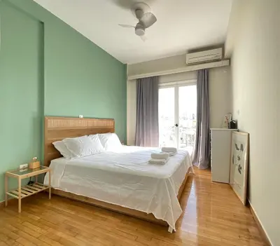 a bedroom with a white bed and a window at Quiet, Sunny & Terrace with Acropolis View in Athens