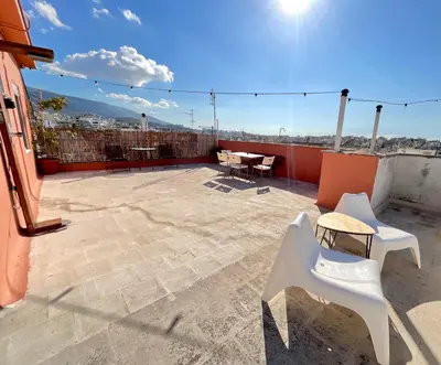a patio with white chairs and tables on a roof at Quiet, Sunny & Terrace with Acropolis View in Athens