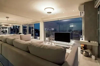 a living room with a large couch and a television at Breathtaking Penthouse Vouliagmeni in Athens