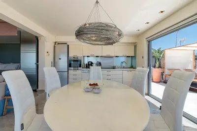 a kitchen and dining room with a white table and chairs at Breathtaking Penthouse Vouliagmeni in Athens