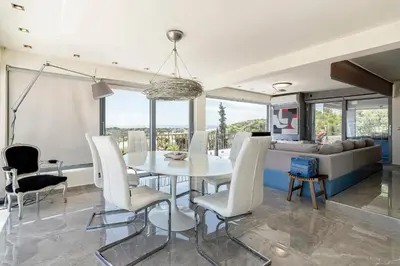 a dining room with a table and chairs and a couch at Breathtaking Penthouse Vouliagmeni in Athens