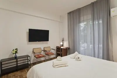 a bedroom with a bed and two chairs and a tv at Serra Relaxing Renovated Apt by Marina & Beach in Piraeus