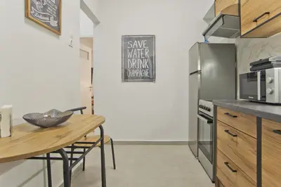 a kitchen with a wooden table and a refrigerator at Serra Relaxing Renovated Apt by Marina & Beach in Piraeus