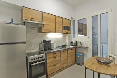 a kitchen with wooden cabinets and a wooden table at Serra Relaxing Renovated Apt by Marina & Beach in Piraeus