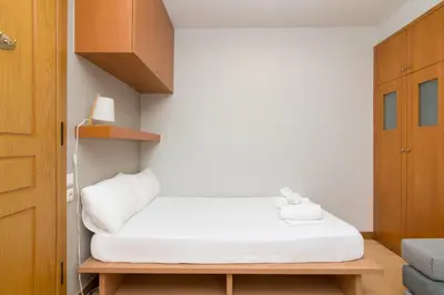 a small room with a white bed and wooden cabinets at Secret Base In Central Athens in Athens