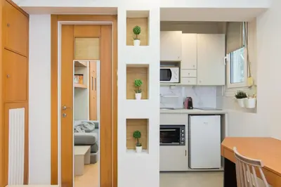 a kitchen and a living room with white cabinets at Secret Base In Central Athens in Athens