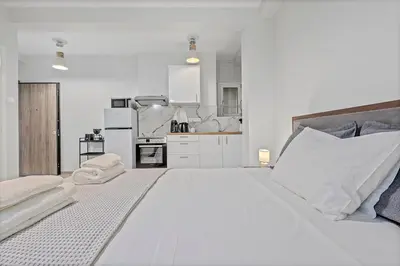 a white bedroom with a large bed and a kitchen at Athens Urban Lifestyle Apartments in Athens