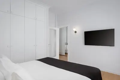 a white bedroom with a bed and a flat screen tv at Acropolis Classy Apartments in Athens