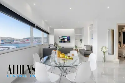 a living room with a glass table and white chairs at Endless Blue Breathtaking View Apt 6fl 2&4ppl in Piraeus