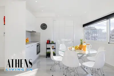 a white kitchen with a table and white chairs at Endless Blue Breathtaking View Apt 6fl 2&4ppl in Piraeus