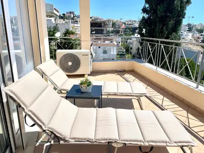 a balcony with two chairs and a table and a heater at Thalassea - Athenian Riviera in Athens