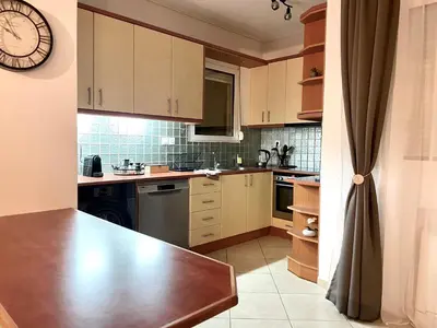 a kitchen with white cabinets and a clock on the wall at Thalassea - Athenian Riviera in Athens