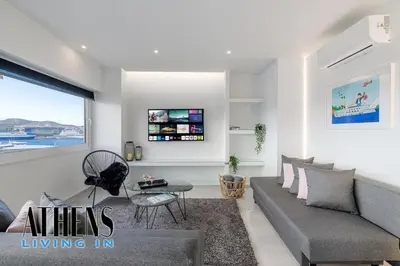 a living room with a couch and a window at Endless Blue Breathtaking View Apt 7fl 2&4ppl in Piraeus