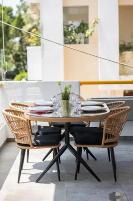 a dining table with rattan chairs on a patio at Peaceful apartment on the Athens Riviera in Athens