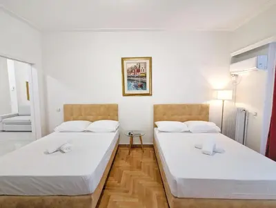 two beds in a room with white walls and wooden floors at Casa Divas Grand Palace Apartments in Athens