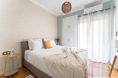 a bedroom with a white bed with a table at Rustic Whispers - close to Acropolis in Athens