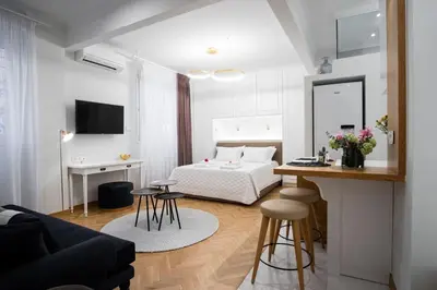 a white bedroom with a bed and a table and stools at Kaplanon Residence Kolonaki in Athens