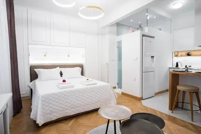 a white bedroom with a bed and a kitchen at Kaplanon Residence Kolonaki in Athens