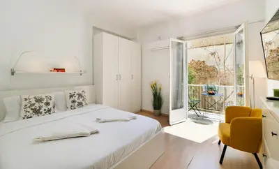 a white bedroom with a bed and a yellow chair at Ideal escape for 2 in Athens