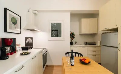 a kitchen with white cabinets and a wooden table at Ideal escape for 2 in Athens