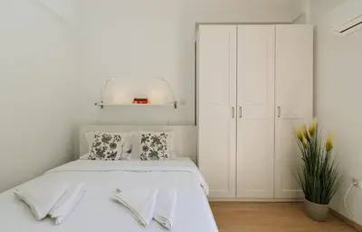 a white bedroom with a bed and a white cabinet at Ideal escape for 2 in Athens