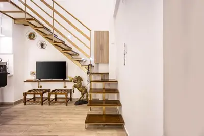 a living room with a staircase and a tv at Loft 61 Charming renovated apartment with a loft! in Athens