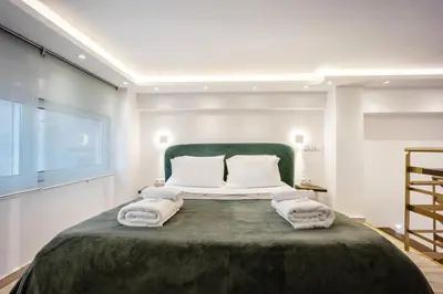a bedroom with a large bed with a green headboard at Loft 61 Charming renovated apartment with a loft! in Athens
