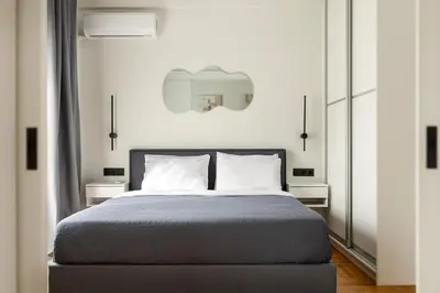 a bedroom with a bed with two tables and a mirror at Modern Designer Apartment in Athens Walk to Plaka & Acropolis in Athens