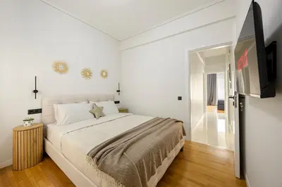 a white bedroom with a large bed and a television at Modern Designer Apartment in Athens Walk to Plaka & Acropolis in Athens