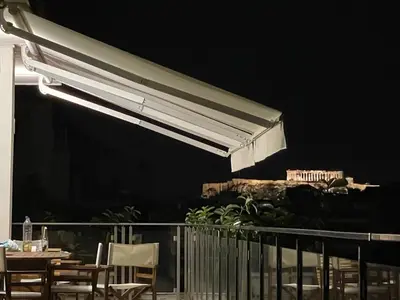 awning over a table and chairs on a balcony at Acropolis & Lycabetus View Helios Residence in Athens