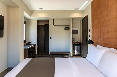 a bedroom with a white bed and a desk at NOOS Acropolis in Athens