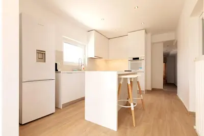 a white kitchen with white cabinets and a counter at Acropolis & Lycabetus View Helios Residence in Athens