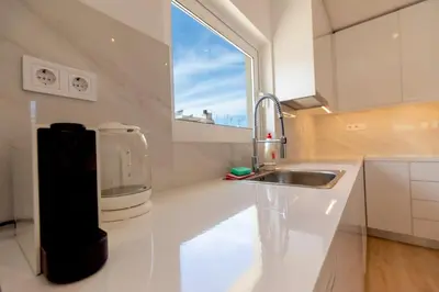 a white kitchen with a sink and a window at Acropolis & Lycabetus View Helios Residence in Athens