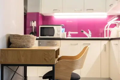 a kitchen with a wooden table and a pink wall at Cozy Hideaway Near the Acropolis in Athens