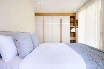 a bedroom with a white bed with blue pillows at The Samirah Luxury Residences in Elliniko in Athens