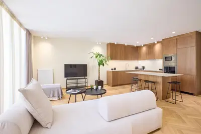 a living room with a white couch and a kitchen at The Samirah Luxury Residences in Elliniko in Athens