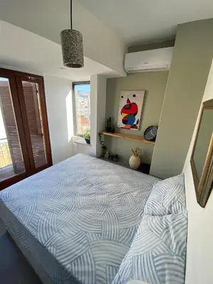 a bedroom with a bed with a blue and white comforter at Mosaics Penthouse studio 360'View in Athens