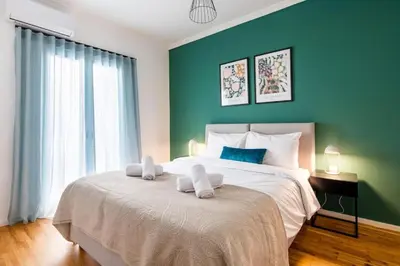 a bedroom with a large bed with a green wall at Urban Haven in Pagrati by MK in Athens