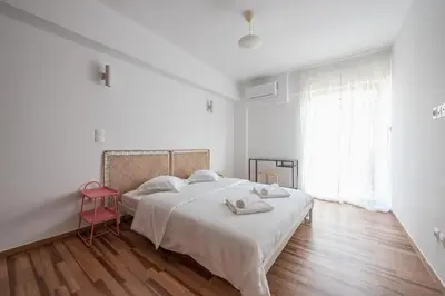 a white bedroom with a bed and a red stool at Zen Bright, Exarchia in Athens