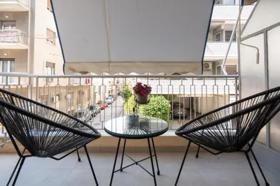 a balcony with two chairs and a table with a vase of flowers at Retro-Modern Echoes in Athens