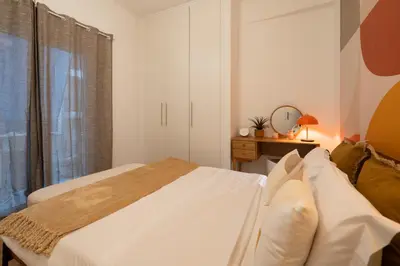 a white bedroom with a bed and a window at Retro-Modern Echoes in Athens